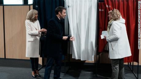 French President Emmanuel Macron (center), next to his wife Brigitte Macron (left), talks to a resident before voting on the first round of the presidential election on Sunday.