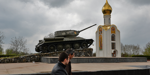 People pass by a Soviet-era tank, now a monument celebrating the Red Army's victory against fascist Germany, in Tiraspol, the main city of Transnistria, Moldova, in April 2014.
