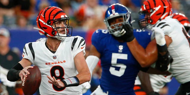 Cincinnati Bengals quarterback Brandon Allen, No. 8, throws a pass as Kayvonne Tibodu of the New York Giants, No. 5, plays him during the first half of an NFL pre-season football game Sunday, August 21, 2022, in East Rutherford, New Jersey
