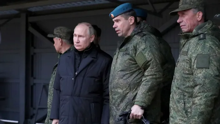 Putin stands next to a soldier under a roofed area